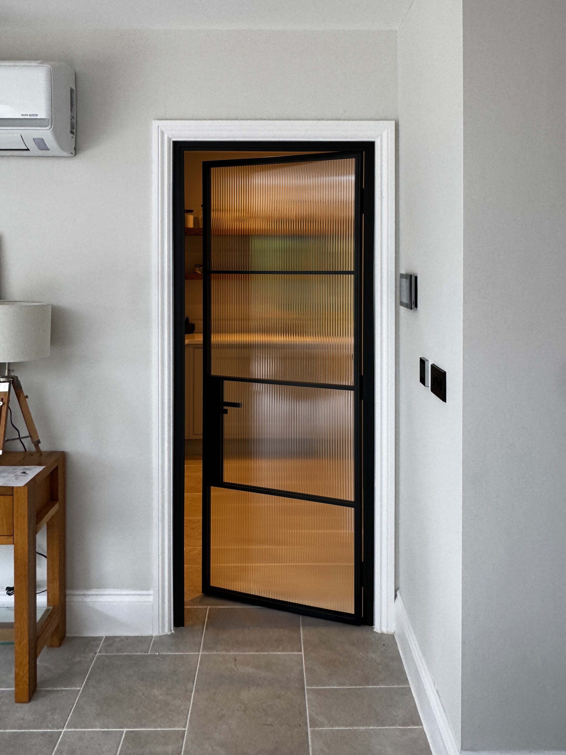 Modern home entrance with frosted glass door and grey tiles