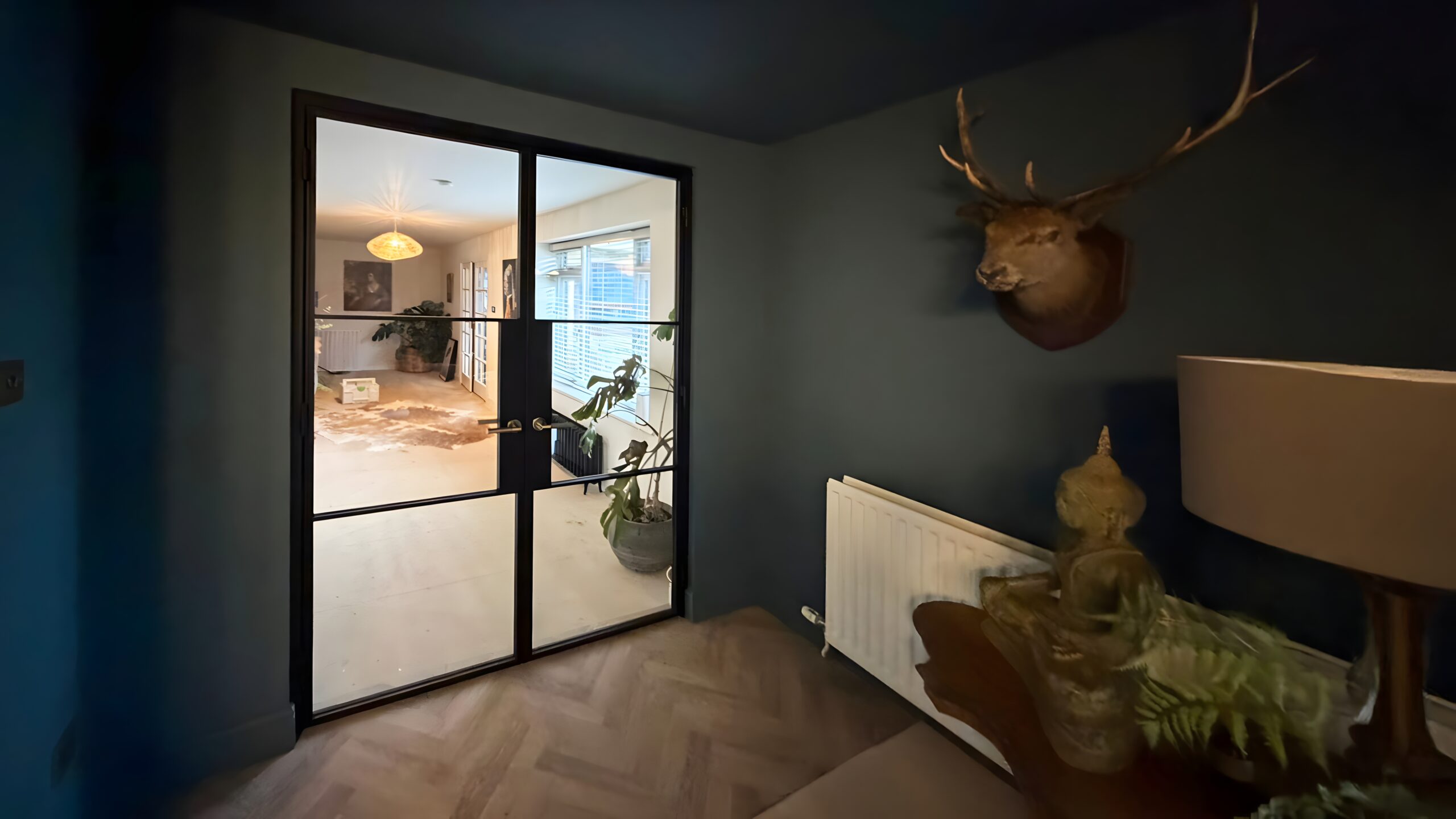 steel-glass-double-doors Modern room with steel glass doors and deer head wall decor